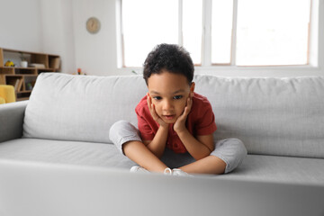 Shocked little African-American boy watching cartoons on laptop at home