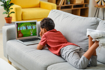 Little African-American boy watching cartoons on laptop at home