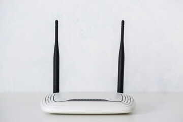 Modern wi-fi router on table near light wall