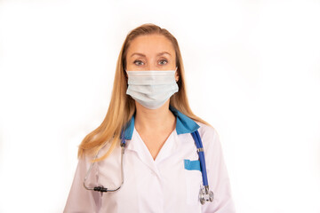 A young doctor girl on a white background in a white coat with a stethoscope around her neck and with her hair loose in a mask