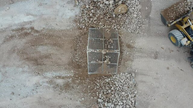 Aerial view of a heavy wheel loader pouring material over sieves for aggregate screening in a quarry