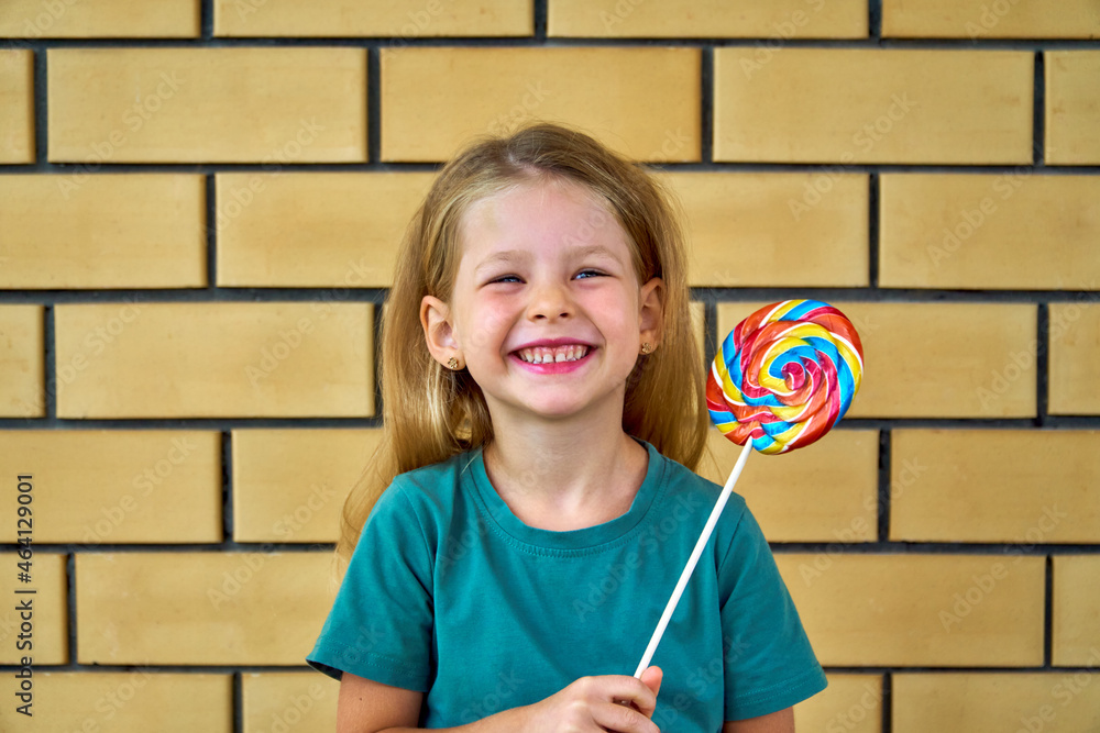 Wall mural happy girl with lollipop. a funny child is playing cheerfully. sweet candy in childhood. celebration