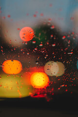 Fotografia de gotas de lluvia sobre parabrisas, con las luces de la calle desenfocadas detras