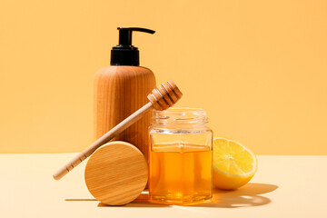 Composition with cosmetic products, honey and lemon on color background