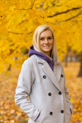 Portrait of a joyful young woman enjoying in autumn park.