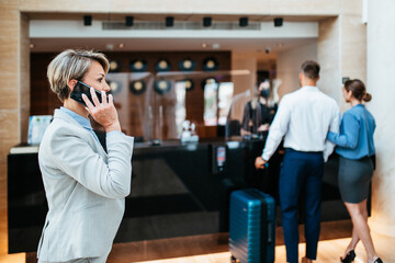 A middle-aged businesswoman arrives at the hotel and and talking on mobile phone.