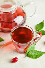 Cup of healthy dogwood berry drink on light background