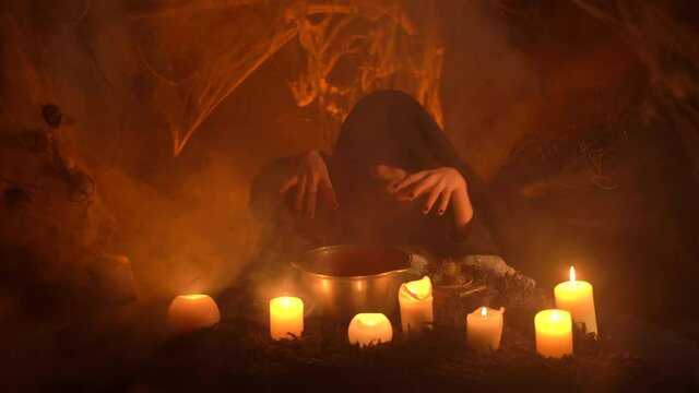 The underworld. Scary witch does voodoo black magic ritual near the Witch's cauldron. Halloween's horror. Scary story. Night tale.