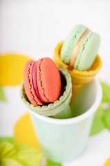 Wafer cup for ice cream with macarons and green gladiolus on a light background