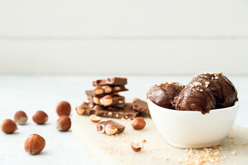 Bowl of tasty chocolate ice cream with nuts on table