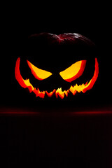 Jack o' lantern in a spotlight glow on a dark  background. Halloween pumpkin with an evil smile