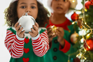 Little African-American girl with Christmas ball at home, closeup