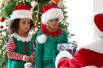 Santa Claus giving present to little African-American children at home