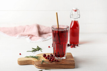 Glass with healthy cranberry juice on light background