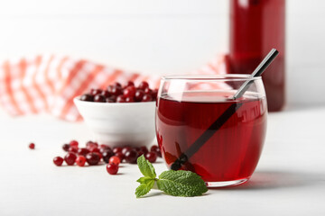 Glass with healthy cranberry juice on light background