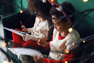 Cute African-American children writing letters to Santa at home