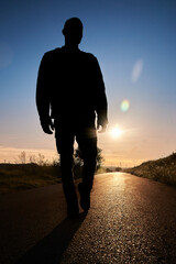 silhouette of a man walking on a sunset