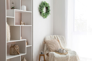 Chair with cups, shelving unit and mistletoe wreath hanging on light wall