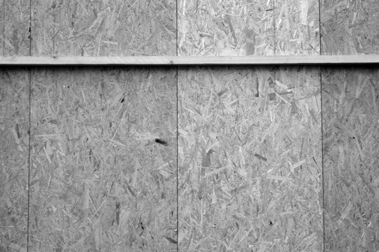 Grobspanplatte oder OSB-Platte als Plakatwand in der Altstadt von Steinhude am Steinhuder Meer bei Wunstorf im Landkreis Hannover, fotografiert in neorealistischem Schwarzwei&szlig;