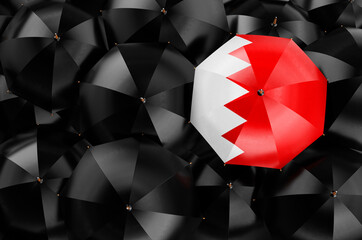 Umbrella with Bahraini flag among black umbrellas, 3D rendering