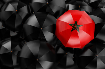 Umbrella with Moroccan flag among black umbrellas, 3D rendering