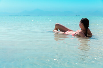 girl in a pink swimsuit enjoying, lying in the sea