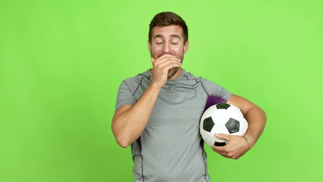 Handsome man playing futbol and doing surprise gesture over isolated background