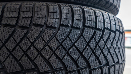 Close-up view of the winter tread of a new tire in shop. Automobile tire for snow road. Selective focus.