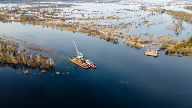 Aerial view of dredge replenish sand in river. Canal is being dredged by excavator. Top view of dredging boat crane.