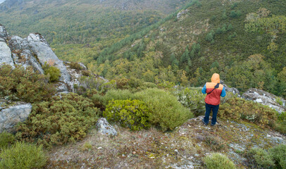 Fototapeta premium Man standing at the edge of a cliff overlooking the mountains below, aerial drone view