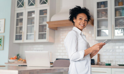A woman surfing the internet. The blogger works on a tablet. The student uses a device. Portrait freelancer prints a message to clients on a social network, workplace at home.