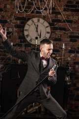 man in suit posing with condenser microphone. Emotional young man with a microphone in his hands