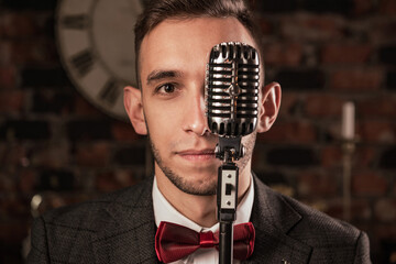 man in suit posing with condenser microphone. Emotional young man with a microphone in his hands