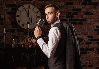 man in suit posing with condenser microphone. Emotional young man with a microphone in his hands