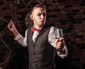 man in suit posing with condenser microphone. Emotional young man with a microphone in his hands - 464140881