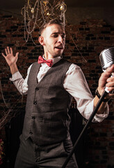 man in suit posing with condenser microphone. Emotional young man with a microphone in his hands