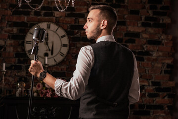 man in suit posing with condenser microphone. Emotional young man with a microphone in his hands