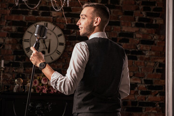 man in suit posing with condenser microphone. Emotional young man with a microphone in his hands