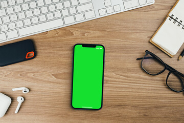 Chroma Key on the smartphone screen on wooden background with a computer beside it. Green screen