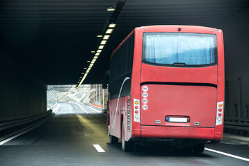 Bus entering a tunnel. . Red bus on the highway.