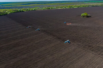 Farmer seeding, sowing crops at field. process of planting seeds in the ground. spring time agricultural activities. Drone photo