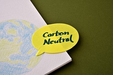 A speech bubble labeled "Carbon Neutral" sits on top of a sketchbook with an illustration of the earth.