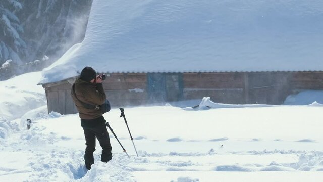 Hiker photographer taking pictures of snowy nature in winter mountains.