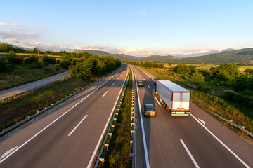 Trucks driving on the asphalt highway.  Trucks driving on asphalt road in a rural landscape. Highway in the mountains. 
