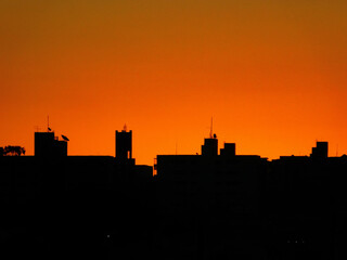 Fototapeta premium City ​​silhouette against sunset. Sky with orange tones.