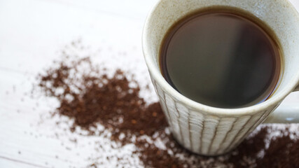 Obraz na płótnie Canvas 木製の床に散らばるグラインドされたコーヒー豆とコーヒカップ