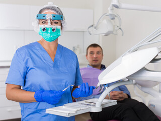 dentist professional filling teeth for man patient sitting in medical chair