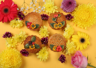 Obraz na płótnie Canvas Colorful flower decorated moon cake Chinese mid autumn festival daisy chrysanthemum mum rose baby breath flower red yellow pink purple violet on yellow background