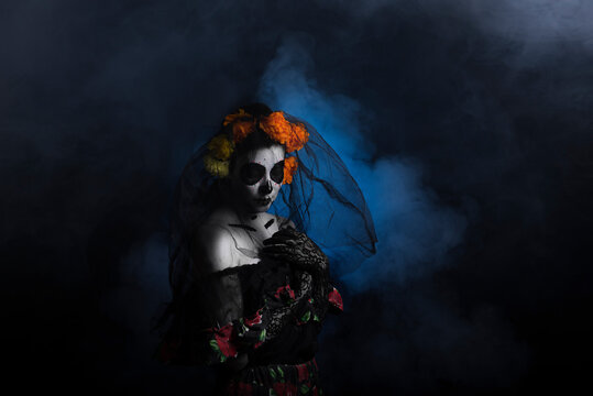 Young woman disguised for halloween as catrina on black background