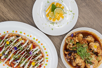 Overhead view of hearty table of flat bread pizza, key lime pie, and tangy roasted cauliflower on a...